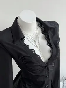 Close-up view of a black V-neck long-sleeve shirt with lace trim and silver necklaces.