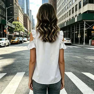 Back view of elegant white cold-shoulder blouse with ruffled sleeves in urban setting