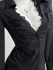 Close-up of black V-neck blouse with lace trim and pleated chest details on mannequin.