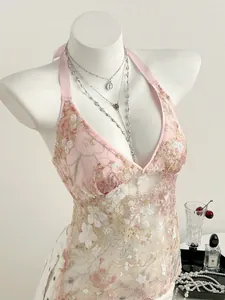 Détail d'un haut licou en dentelle rose orné de paillettes et d'un motif floral élégant et chic.