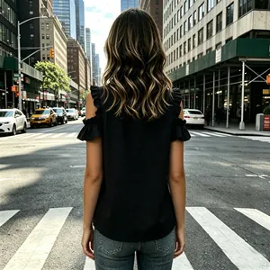 Stylish black cold-shoulder blouse with ruffled sleeves shown from a back view on a street.