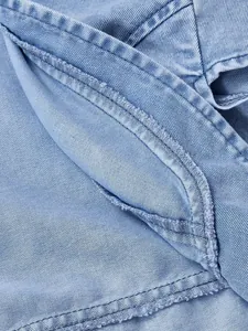 Dettaglio del tessuto denim azzurro con cuciture rinforzate e bordi sfrangiati