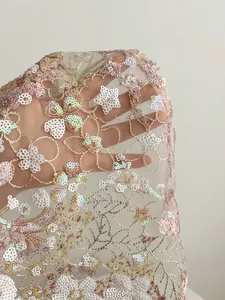 Gros plan détaillé de broderies de paillettes fleurs et étoiles sur dentelle rose délicate
