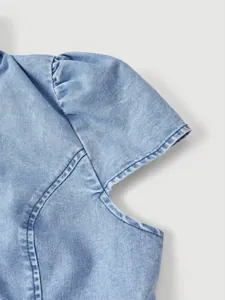 Primo piano dettagliato del design della manica a sbuffo di una giacca di jeans azzurra