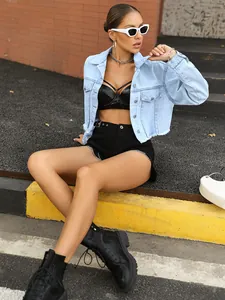 Light blue cropped denim jacket with frayed hem shown in an urban outdoor setting
