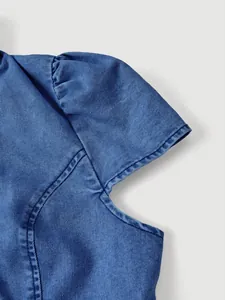 Dettaglio macro che mostra la manica a sbuffo e le cuciture di una giacca di jeans blu