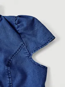 Dettaglio di giacca di jeans blu con maniche a sbuffo e cuciture di alta qualità visibili