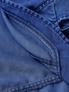 Vista macro che mostra le cuciture resistenti e la trama della giacca in denim blu