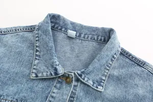 Close-up detail of the classic spread collar and vintage metal button on blue denim jacket