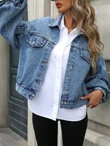 Primo piano di una giacca di jeans corta azzurra dal taglio ampio con bottoni metallici