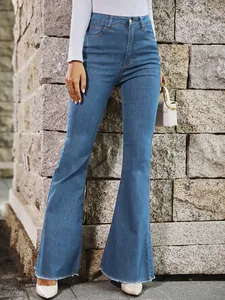 High-waist stretch denim flared jeans met gerafelde zoom tegen een stenen muur