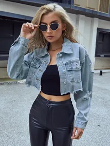 Chaqueta vaquera corta azul claro de moda con detalles desgastados en escena urbana.