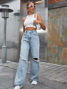 Détail d'un jean en denim bleu clair à taille haute, déchiré et à jambes larges, porté.