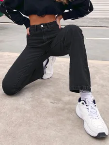 Close-up of black high-waisted straight jeans paired with white sneakers
