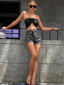 Modella indossa pantaloncini di jeans grigi a vita alta e top halter nero in città.