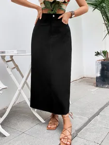 Detailed view of a high-waisted black denim midi skirt with raw hem in lifestyle setting