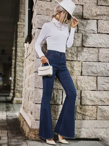 Stijlvol model in flare jeans met hoge taille tegen een getextureerde stenen muur