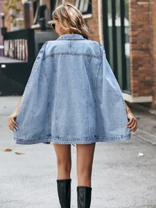 Back view of an oversized light blue denim cape jacket in a street style setting