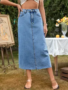 High-waist A-line denim midi skirt with raw hem and light blue wash in a garden setting