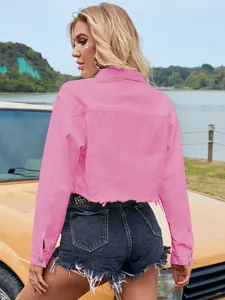 Back view of a trendy pink cropped denim jacket worn by a model in an outdoor setting.