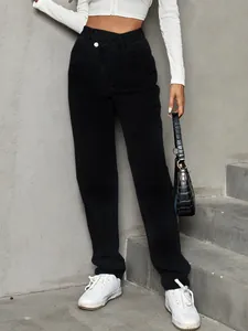 Detailed view of high-waisted black denim pants with an asymmetrical cross waistband.