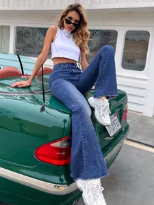 Modieuze vrouw in blauwe flared jeans met hoge taille op een groene vintage auto