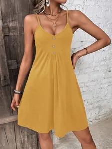 Close-up of mustard yellow strap dress with front button detail and rustic background