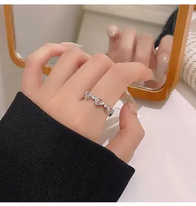 Nahaufnahme eines silbernen offenen Rings mit rosa herzförmigen Zirkonsteinen an der Hand