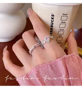 Nahaufnahme eleganter Silberringe mit rosa herzförmigem Zirkon am Finger getragen