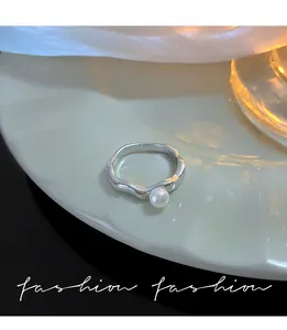 Nahaufnahme eines silbernen, welligen offenen Rings mit einer einzelnen weißen Perle