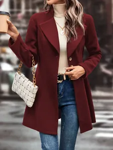 Chic burgundy lapel woolen coat styled with white bag and jeans in an urban setting.