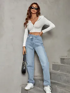 Casual high-waisted light blue jeans with unique crossover waist design on concrete stairs
