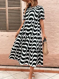 Detail view of a loose-fitting dress with black and white wavy print and puff sleeves