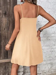 Back view of a casual solid apricot camisole mini dress against a rustic brick wall