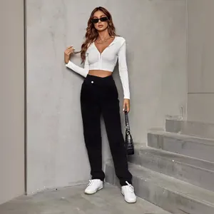 Model in high-waist loose black denim pants with white crop top and white sneakers.