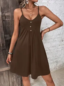 Close-up showing the brown camisole dress with decorative buttons and pleated design