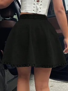 Detail of high-waisted black denim flared mini skirt paired with a white corset top.