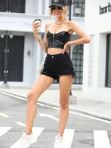 Modella che indossa pantaloncini di jeans neri strappati alla moda su una strada cittadina.