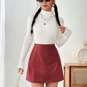 Vue détaillée d'une mini-jupe trapèze en cuir PU rouge portée avec un pull blanc.