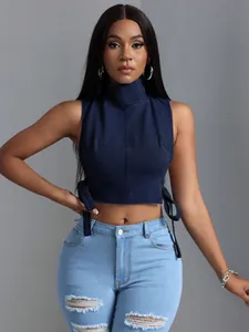 Primo piano di un crop top in denim blu navy con collo alto e dettagli stringati laterali.
