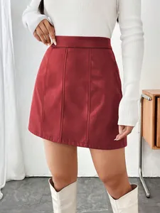 Détail d'une jupe courte trapèze en similicuir rouge à taille haute et surpiqûres.