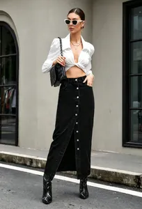 Detail van een zwarte denim maxi-rok met knoopsluiting aan de voorkant en laarzen