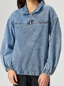 Dettaglio del pullover in denim azzurro ampio con mezza zip e orlo elastico alla moda