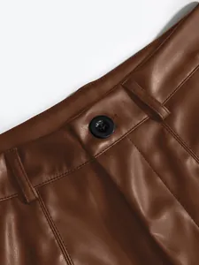 Detailed macro shot of brown PU leather shorts featuring waist button and stitching