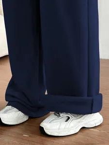 Vue détaillée de l'ourlet du pantalon large bleu marine avec des baskets blanches