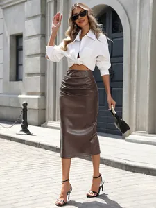 Jupe midi froncée en cuir PU marron portée par un mannequin dans une rue ensoleillée.
