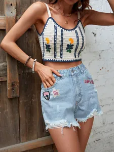 Primo piano di pantaloncini di jeans a vita alta usurati con toppe ricamate.