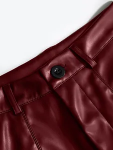 Close-up of burgundy PU leather shorts waistband with button and stitching details.
