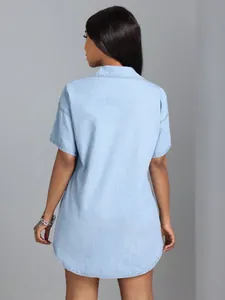 Back view of a loose light blue denim shirt with a turn-down collar and short sleeves.