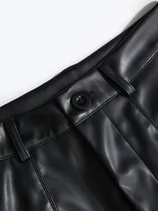 Close-up of black PU leather shorts waistband featuring a button and belt loops.